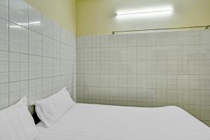 a bedroom with a white bed with white tiled walls at OYO 86379 Dream Palace Guest House Near Marina Beach in Chennai