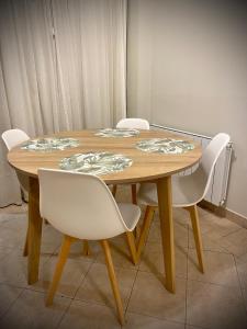 uma mesa de madeira com cadeiras brancas à volta em Gertrudis - Central Point Apartments em Salta