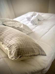 uma cama branca com uma almofada e toalhas em Gertrudis - Central Point Apartments em Salta