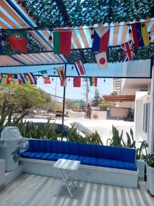 un banco azul bajo un paraguas con banderas. en Mar de Indias House en Cartagena de Indias