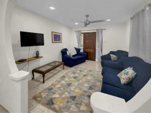 un soggiorno con divano blu e TV di Private 3BR Tropical Paradise near Oistins a Christ Church