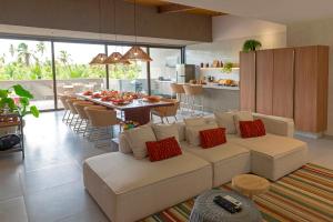 a living room with a white couch and a kitchen at Kanui Garden Milagres in São Miguel dos Milagres