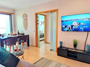 a living room with a tv on a wall at Beach Condo with Atlantic Ocean View by BeCherish in Olhos de Água