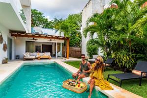 a man and a woman sitting next to a swimming pool at Villa Ek'Balam & Villa Flamingo, Luxury Villas, Private Pool, Private Garden, Jacuzzi, 24h Security in Tulum