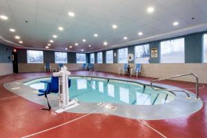 una piscina en una habitación con sillas y mesas en Holiday Inn Express Hotel & Suites Swansea, an IHG Hotel en Swansea