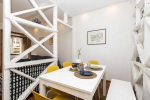 a white dining room with a white table and yellow chairs at Typical Portuguese Apartment in São Bento in Lisbon