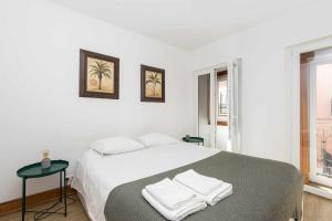 a white bedroom with a bed with towels on it at Typical Portuguese Apartment in São Bento in Lisbon