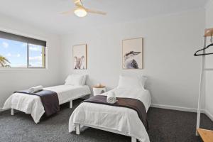 two beds in a room with white walls and a window at Waterfront Townhouse - Picturesque Marina Views in Port Lincoln