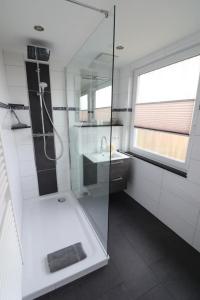 La salle de bains blanche est pourvue d'une douche et d'un lavabo. dans l'établissement Appartementhaus-Kogge-Wohnung-7, à Cuxhaven