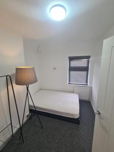 a small room with a bed and a lamp at Emergency - Bedrooms Only in Birkenhead
