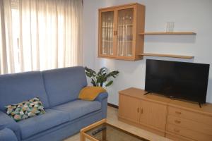 un soggiorno con divano blu e TV a schermo piatto di Apartamento Puente a Portonovo