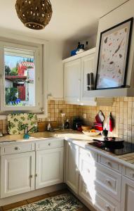 eine Küche mit weißen Schränken und einem Fenster in der Unterkunft La terrasse à Erromardie in Saint-Jean-de-Luz