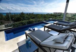 a swimming pool with two lounge chairs and a table at Luxury Condo between 5th Avenue and the Beach in Playa del Carmen