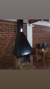 Una chimenea en una habitación con una mesa y una pared de ladrillo en Las Cecilias 2 en San Vicente