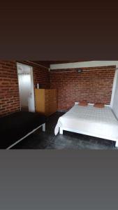 ein Schlafzimmer mit einem weißen Bett und einer Ziegelwand in der Unterkunft Las Cecilias 2 in San Vicente