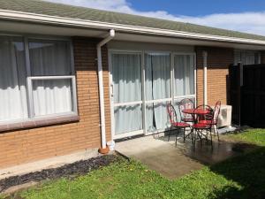 dos sillas y una mesa frente a una casa en Coachman Motel, en Christchurch