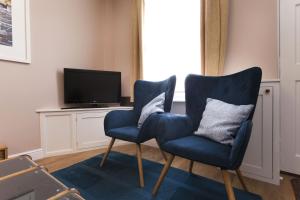 twee blauwe stoelen in een woonkamer met een tv bij Highfield Grove in Nottingham