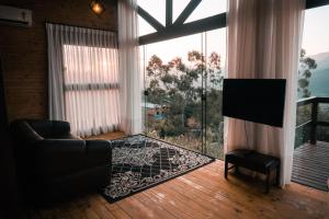 a living room with a couch and a large window at Cabanas nos Canyons in Praia Grande