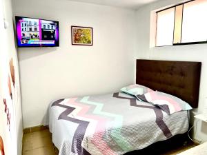 Un dormitorio con una cama y un televisor en la pared. en Lindo dpto con vista al jardin, internet y cable, en Lima