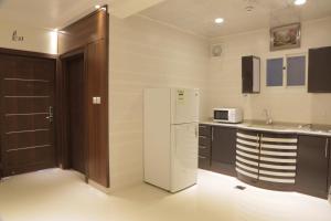 a kitchen with a white refrigerator and a sink at شقق الكادي in Najran