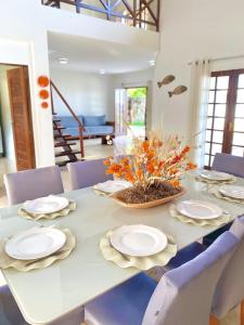 een witte tafel met stoelen, borden en bloemen erop bij Casablanca Beira Mar, 5 Suítes, Praia Tabuba AL in Barra de Santo Antônio