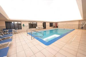 a large swimming pool in a large room with chairs at Holiday Inn Express Hotel & Suites East Lansing, an IHG Hotel in East Lansing