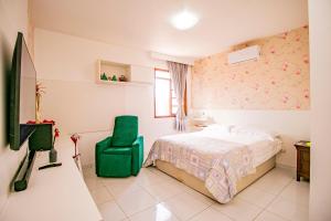 a bedroom with a bed and a green chair at Casa em Campina Grande in Campina Grande