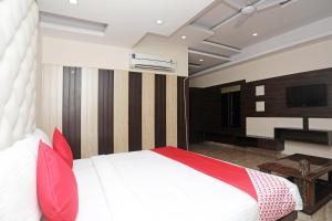 sypialnia z białym łóżkiem z czerwonymi poduszkami i telewizorem w obiekcie Hotel Subhadra Residency w mieście Anūpnagar