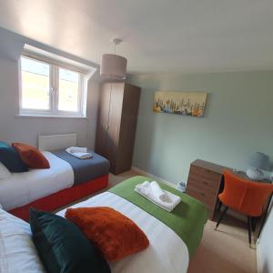 a bedroom with two beds and a desk with a chair at Ideal Coach House in Swindon