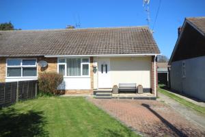 une maison blanche avec un banc dans la cour dans l'établissement Cosy Two Bedroom Bungalow in Hutton Brentwood with Free Parking & Garden, à Hutton