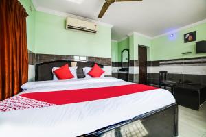 um quarto com uma cama grande e almofadas vermelhas em OYO Dkr Regency em Kurnool