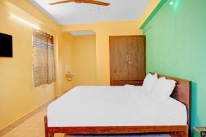 1 dormitorio con cama blanca y ventilador de techo en Flagship Veda Residency, en Warangal