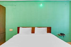 1 dormitorio con 1 cama blanca grande y pared verde en Flagship Veda Residency, en Warangal