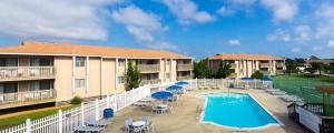 una piscina en un complejo con sillas y sombrillas en Sea Scape Beach and Golf Villas en Kitty Hawk