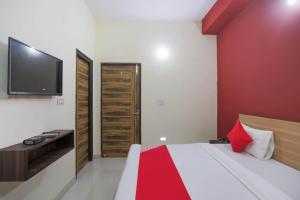 a bedroom with a bed with a red wall at OYO Sewa Residency in Faridabad