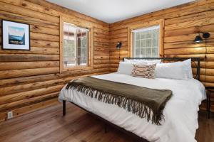 Cama en habitación con paredes de madera en Pine Loop Log Cabin, en La Pine