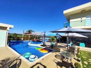 a swimming pool with tables and umbrellas next to a building at Chácara Arena JK com Piscina integrada com Sauna e Hidromassagem in Ibiúna