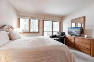 um quarto com uma cama, uma televisão e uma cadeira em Townsend Place Ski In Ski Out Access em Beaver Creek