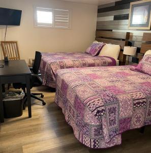 a room with two beds and a desk and a table at Purple Sage Motel in Panguitch