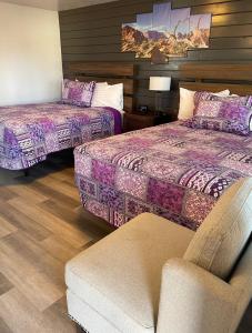 una habitación de hotel con 2 camas y una silla en Purple Sage Motel en Panguitch