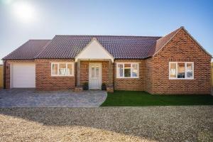 a red brick house with a garage at Stylish New Bungalow - Ideal for up to 10 in Welney