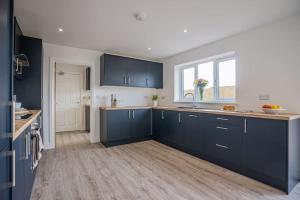 une cuisine avec des placards bleus et un comptoir dans l'établissement Stylish New Bungalow - Ideal for up to 10, à Welney