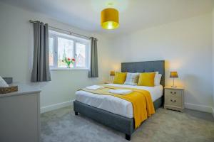 a bedroom with a bed with yellow pillows and a window at Stylish New Bungalow - Ideal for up to 10 in Welney