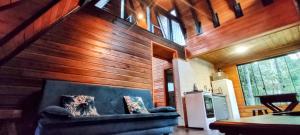 a living room with wooden walls and a blue couch at Chalés Estância Cachoeira do Avencal in Urubici
