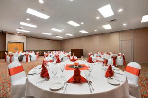 a banquet hall with white tables and red chairs at Red Lion Hotel Gillette in Gillette +39 photos