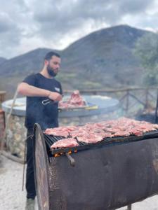 um homem ao lado de uma grelha com carne em Azienda Agricola Ausono em Piaggine