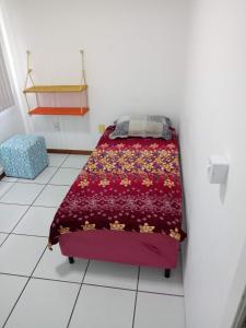 a small bedroom with a bed with a red blanket at Hostel Da Penha in Vila Velha