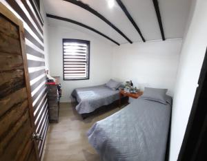 1 dormitorio con 2 camas individuales y ventana en CABAÑAS MIRASOL ALGARROBO, en Yeco