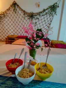 3 Schüsseln Essen auf einem Tisch mit Löffeln in der Unterkunft Backpacker Galle Hostel in Galle