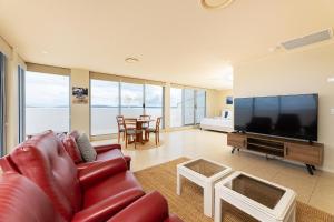 a living room with a couch and a large screen tv at The Crest Penthouse 902 in Forster